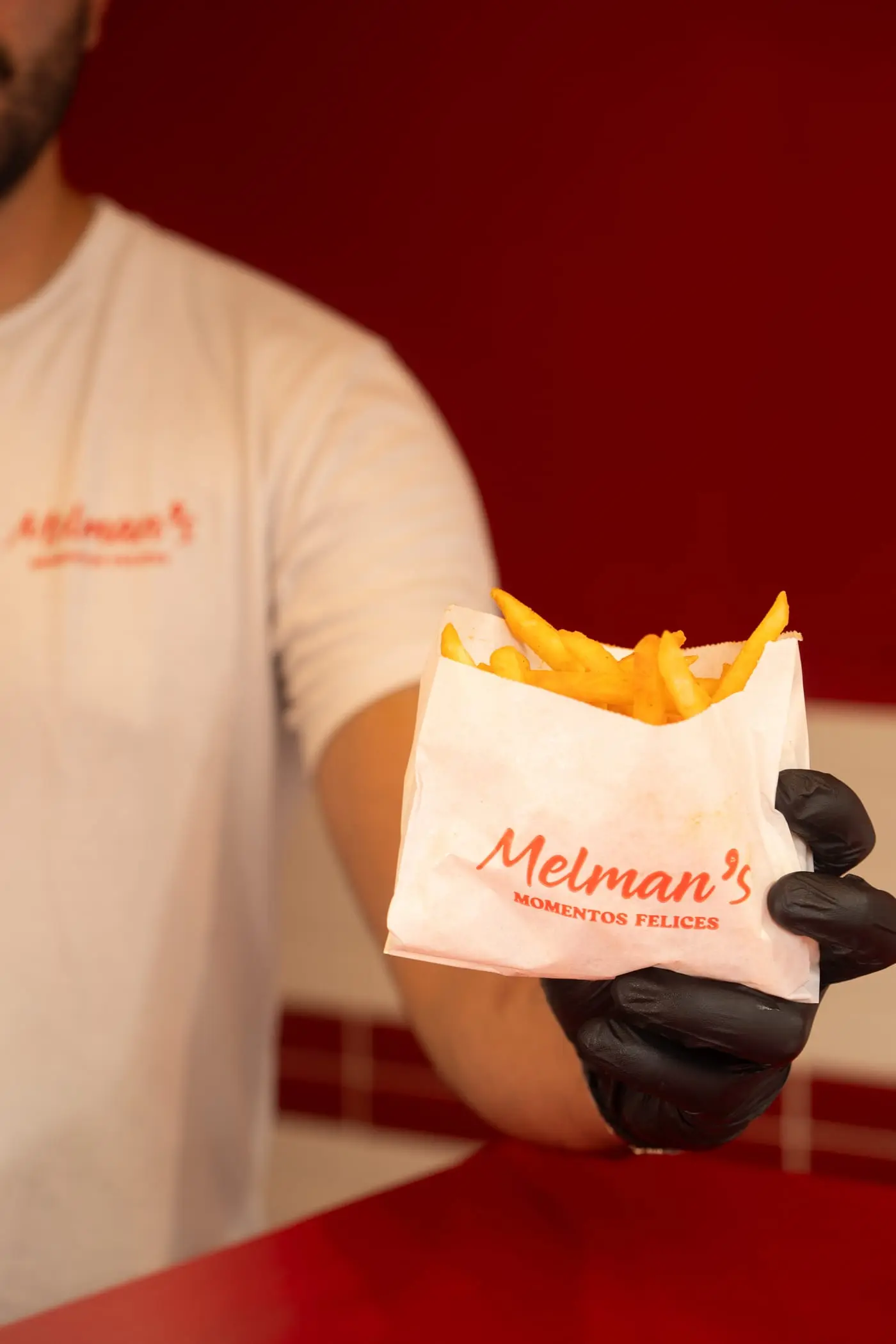 Integrante del equipo de Melman’s entregando una bolsa de papas fritas