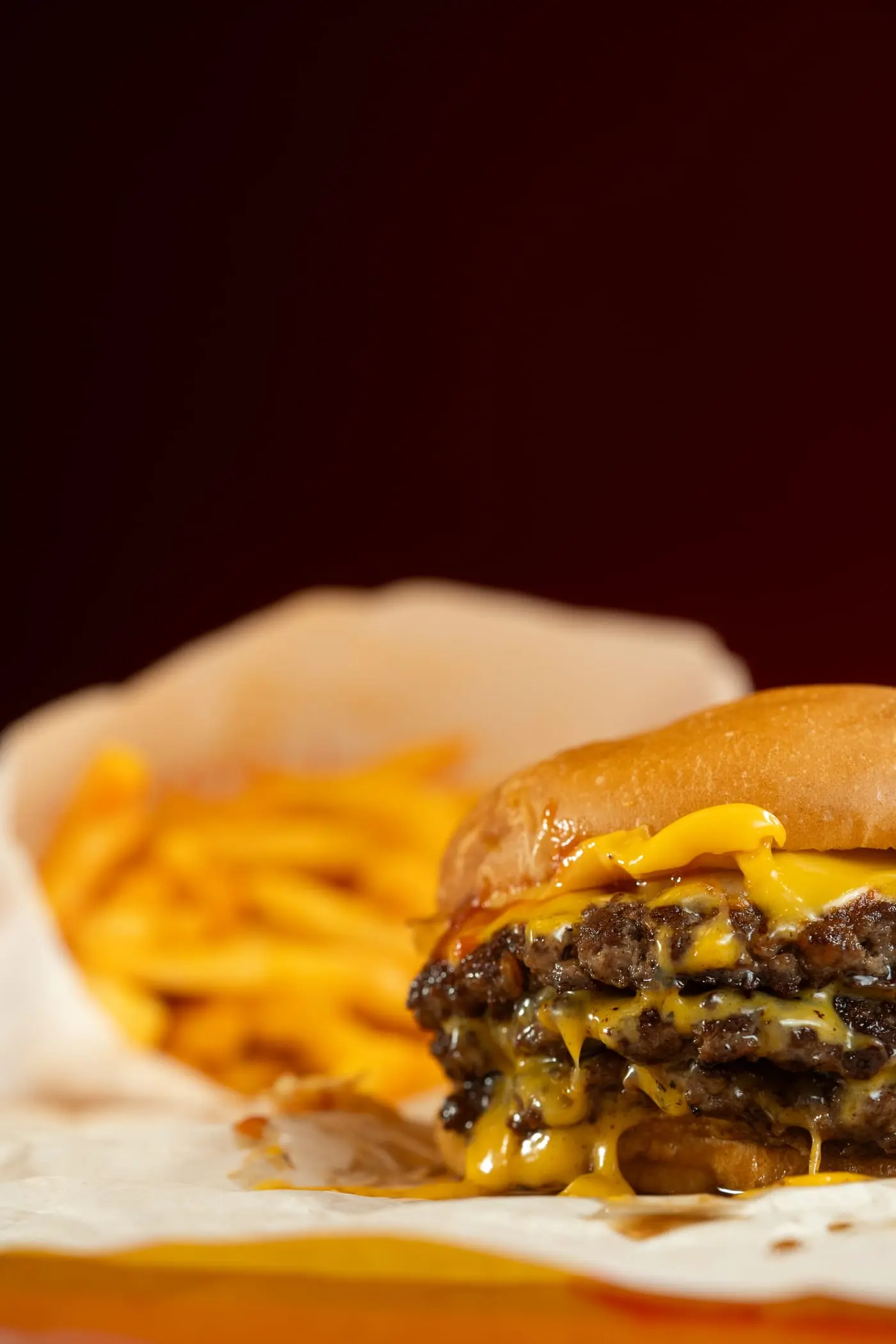 Hamburguesa doble con queso y papas fritas de fondo