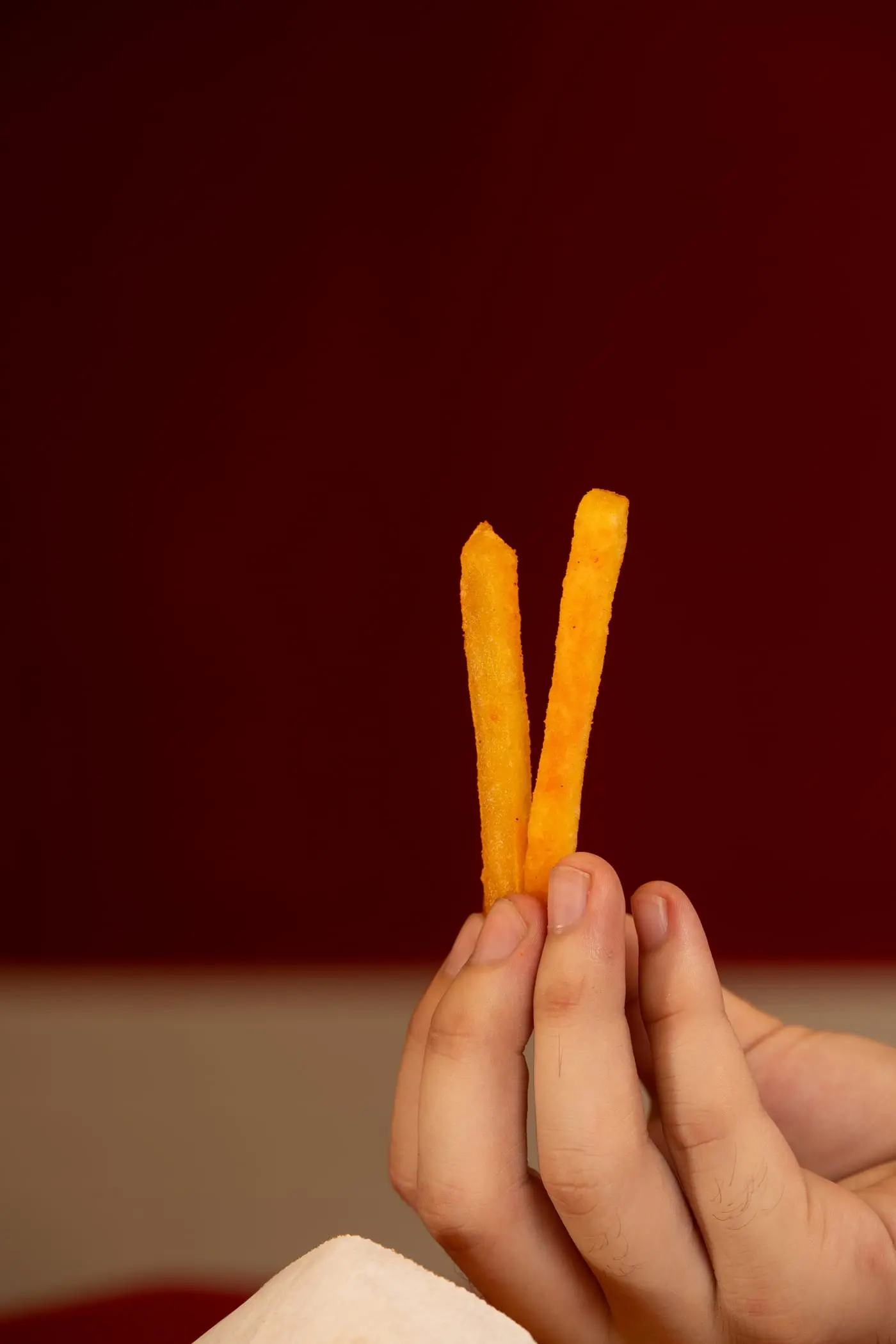 Dos papas fritas crocantes sostenidas con los dedos