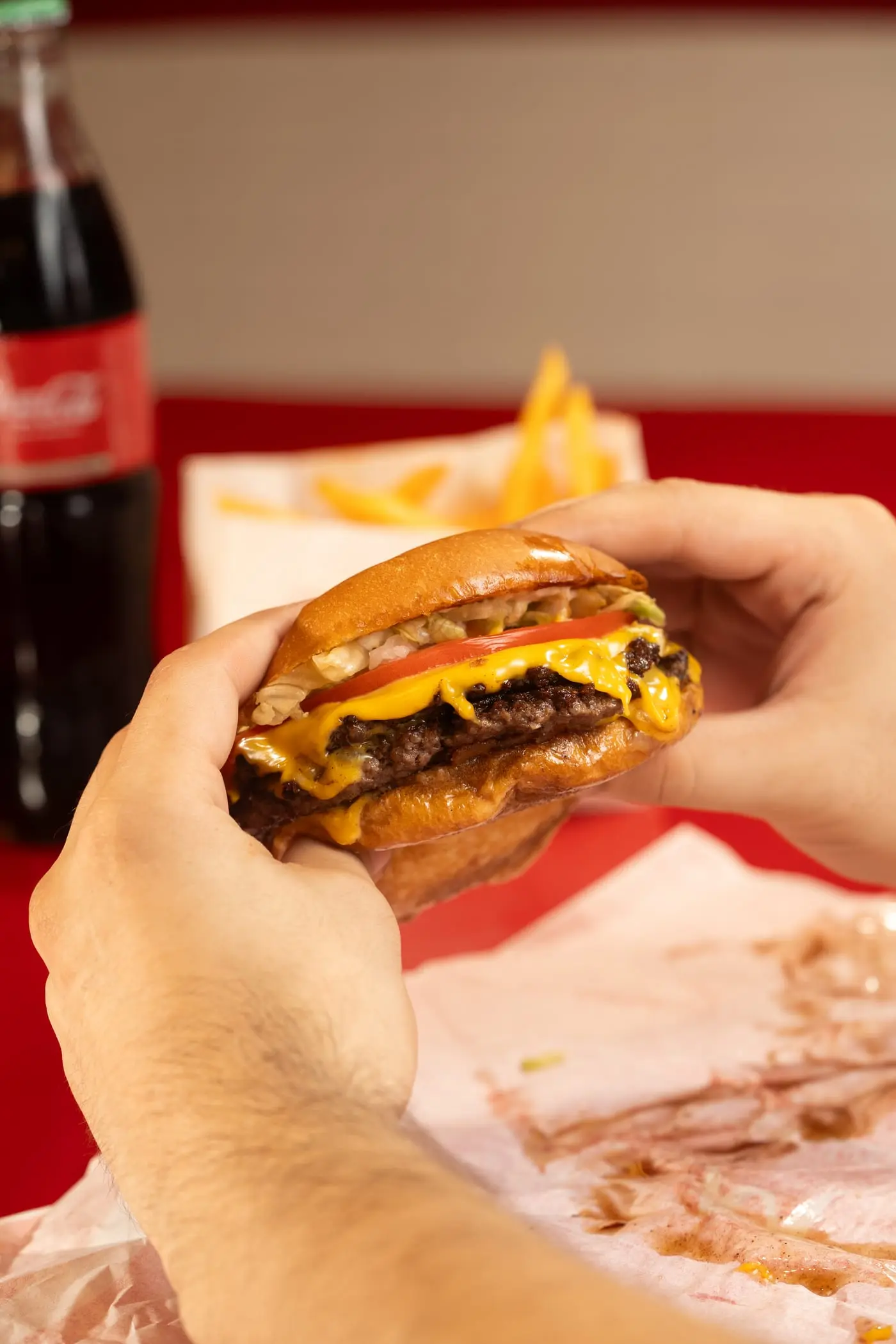 Hamburguesa doble con queso y una Coca-Cola de vidrio de fondo