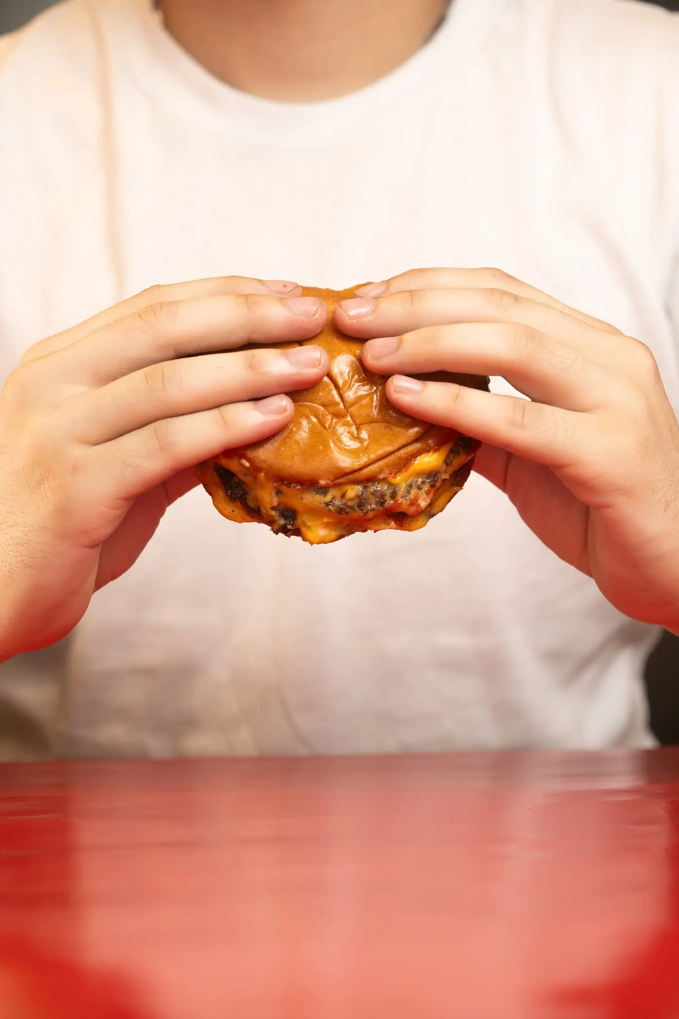 Hamburguesa smash sostenida con las manos
