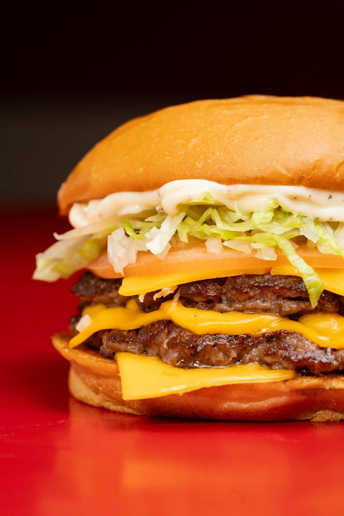 Primer plano de una hamburguesa doble con cheddar, lechuga y tomate